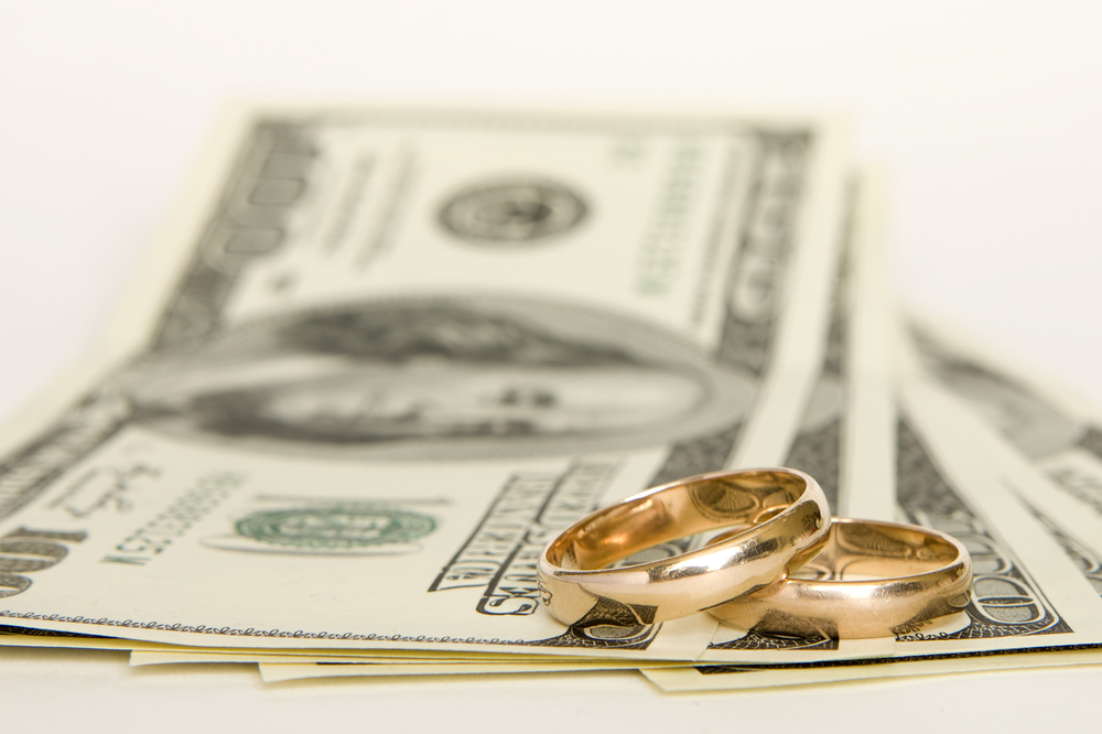 money and wedding rings show how important it is for spouses to attend financial planning meetings together.
