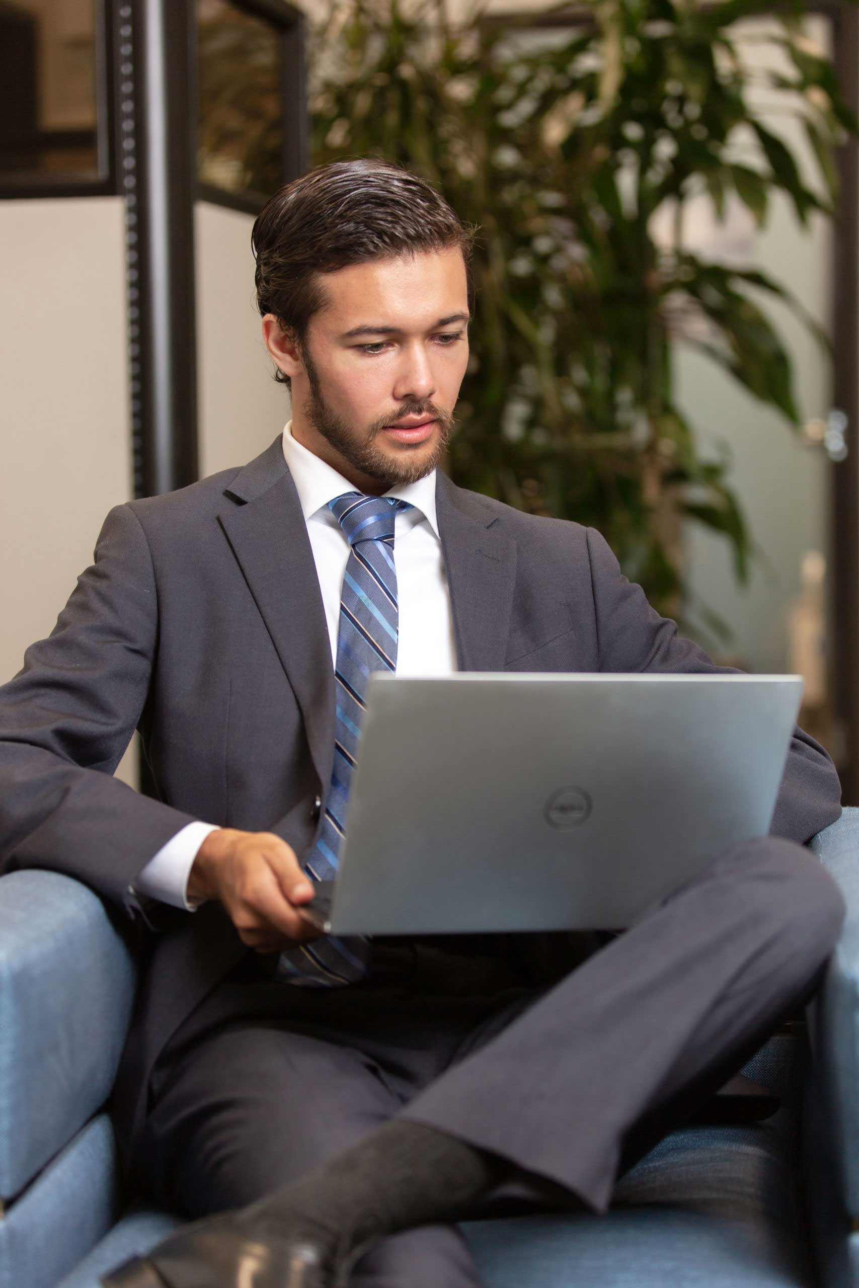 San-Diego-financial-planner-scaled-1 Businessman using a laptop while sitting on an armchair